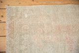 Distressed Oushak rug edge with fringe, showing faded colors and visible foundation.