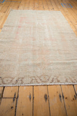 Low pile texture and short fringe of a distressed Oushak rug, revealing worn blush tones.