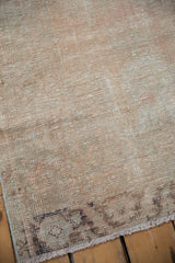 Distressed pile texture of the vintage Oushak rug, showing faded blush, ivory, and fringe.