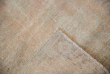 Vintage distressed Oushak rug corner showing worn pile, exposed foundation, and secured fringe.