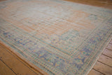 Distressed apricot field and faded blue-green border of a vintage Oushak rug corner.