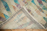 Distressed vintage Tulu rug folded corner, revealing colorful pile and striped hand-knotted foundation.