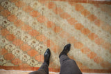 Angled view of the distressed Oushak runner's texture, showing low pile in pale rust and ivory.