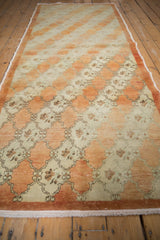 Angled view of a vintage Oushak runner with its diagonal rust and ivory trellis design.
