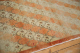 Angled view of a distressed Oushak runner's diagonally oriented rust and ivory trellis pattern.