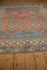 Distressed vintage Melas carpet edge with geometric patterns in faded red and blue.