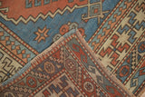 Distressed Melas carpet with geometric patterns in brick red, sky blue, and ivory.