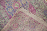 Distressed vintage Oushak rug's folded corner reveals worn pile, foundation, and fringe.