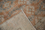 Distressed Oushak rug pile, rust and gray tones, folded corner reveals beige foundation.