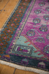 Distressed Oushak runner's magenta field, pale mint plant motifs, and rams horn border.
