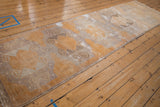 Secured corner of a distressed vintage Oushak runner, showing gold, ivory, and silver tones.