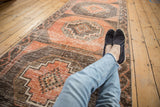 Distressed Oushak runner with repeating stepped medallions in terra cotta and charcoal.