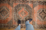 Distressed vintage Oushak runner's textured surface in dusty terra cotta and charcoal with feet.