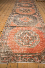 Distressed vintage Oushak runner pile, revealing stepped medallions in dusty terracotta and charcoal.