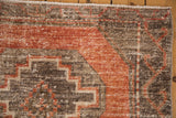 Distressed Oushak runner's textured pile, dusty terra cotta, and charcoal geometric pattern.