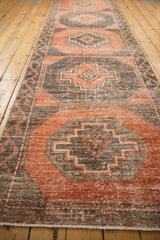 Distressed vintage Oushak runner's dusty terra cotta and charcoal stepped pattern with visible texture.