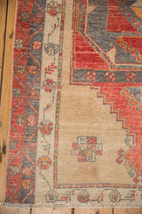 Distressed vintage Oushak runner corner, brick red, charcoal patterns, beige border, and fringe.