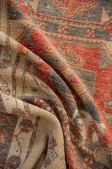 Distressed Oushak runner pile showing brick red, charcoal, and sand-toned patterns.