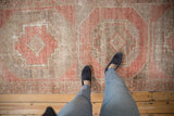 Distressed vintage Oushak runner with artfully worn pile, muted blush red, and geometric patterns.