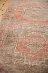Distressed Oushak runner with blush red geometric patterns and visible foundation.