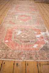 Distressed vintage Oushak runner detail: blush red geometric border, worn tones, visible foundation.
