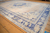 Distressed Oushak carpet displaying faded beige tones and a bold cobalt blue border.