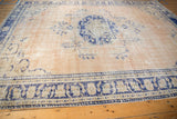 Distressed Turkish Oushak rug displaying asymmetric cobalt blue border and worn abrashed beige field.