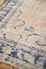 Distressed Oushak carpet detail, showing faded cobalt blue vines on a worn beige ground.