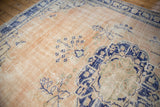 Distressed Oushak rug with cobalt blue floral vines on an abrashed beige ground.