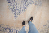 Worn vintage Oushak carpet with faded cobalt blue design on an ivory-beige field.