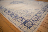 Distressed hand-knotted Turkish Oushak rug corner, showing cobalt blue border and ivory field texture.