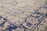 Distressed Oushak rug pile with worn ivory, visible foundation, and faded cobalt blue motifs.