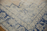 Worn cobalt blue floral motifs on distressed vintage Oushak rug corner with ivory field.