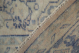 Distressed hand-knotted pile with scattered blue patterns and a woven fringed edge.