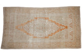 Distressed vintage Oushak rug with burnt orange stepped medallion on an abrashed beige ground.