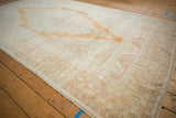 Faded rust border patterns, abrash ivory ground, and fringe of a distressed Oushak rug.