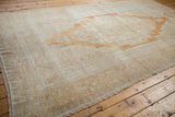 Distressed Oushak carpet corner, showing intact selvage, short fringe, and faded sand tones.