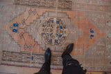Distressed Oushak runner with terracotta, sand, and blue floral vinery patterns.
