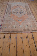 Worn pile and red side selvage on vintage Oushak runner with terracotta and sand motifs.