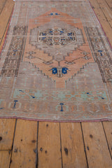 Faded mint and terracotta floral checker motifs at secured end of vintage Oushak runner.