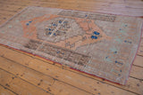 Distressed Oushak rug corner details even pile wear and original selvage in faded terracotta and mint.
