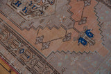 Distressed Oushak runner detail showing terracotta field, stepped contours, and bright blue floral motifs.