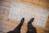Distressed Oushak rug showing worn foundation, faded floral pattern in pale rose, ocean green.