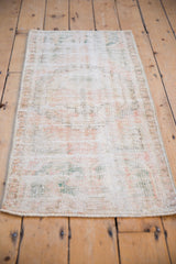 Distressed Oushak runner texture: faded pale rose, ivory, ocean green, visible knot heads.
