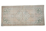 Distressed vintage Oushak rug runner featuring faded scalloped medallion in pale rose, ivory, and seafoam green, 1'10