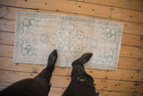 Distressed Oushak runner corner displaying worn pile, pale rose, and seafoam green.