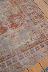 Distressed Oushak rug corner with rust and ivory stepped patterns and barber pole border.