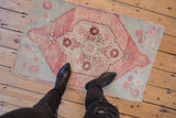 Distressed vintage Oushak rug corner, pale raspberry and sea foam green floral motifs.