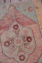 Distressed vintage Oushak rug's pale raspberry and sea foam floral spandrel and medallion detail.