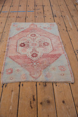 Distressed Oushak rug corner with pale raspberry floral spandrel, sea foam green, and fringe.